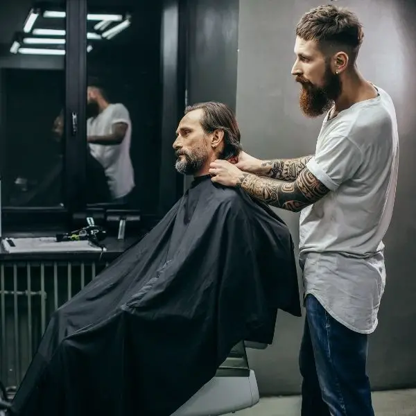 Man getting his har and beard cut by barber