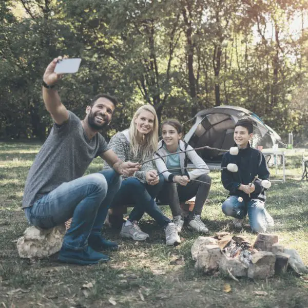 A husband and father camping with his family making smoress