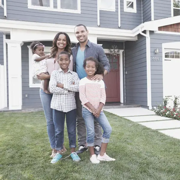 A husband and father standing infront of new home with family