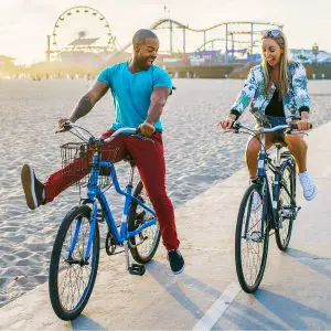 Boyfriend and Girlfriend riding bikes near beach and having fun together