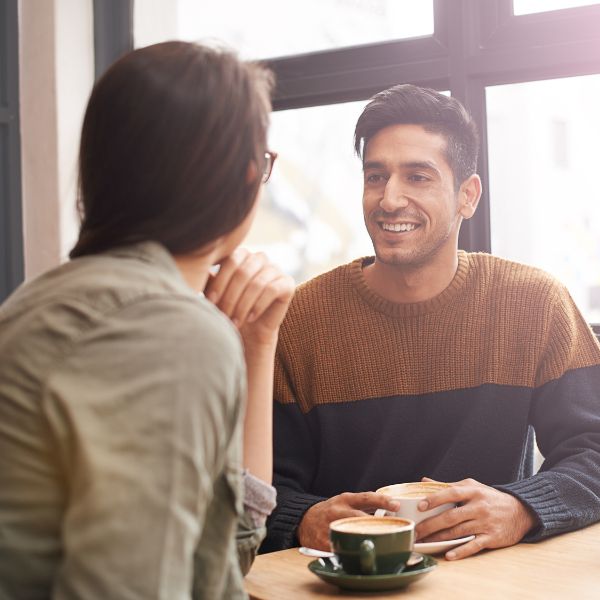 Man and woman smiling and having coffee on first date