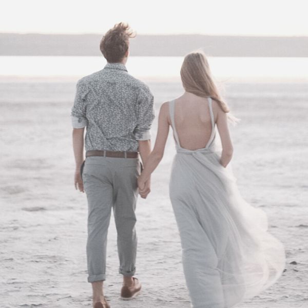 Man and woman walking on the beach holding hands