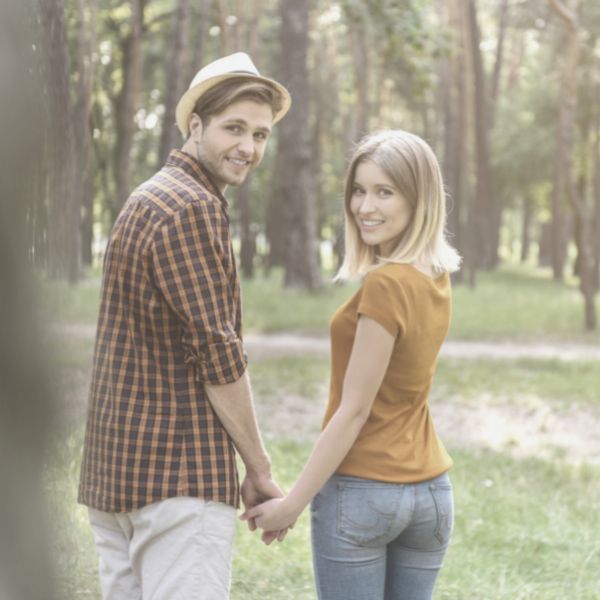 Guy holding girls hand while walking in the park