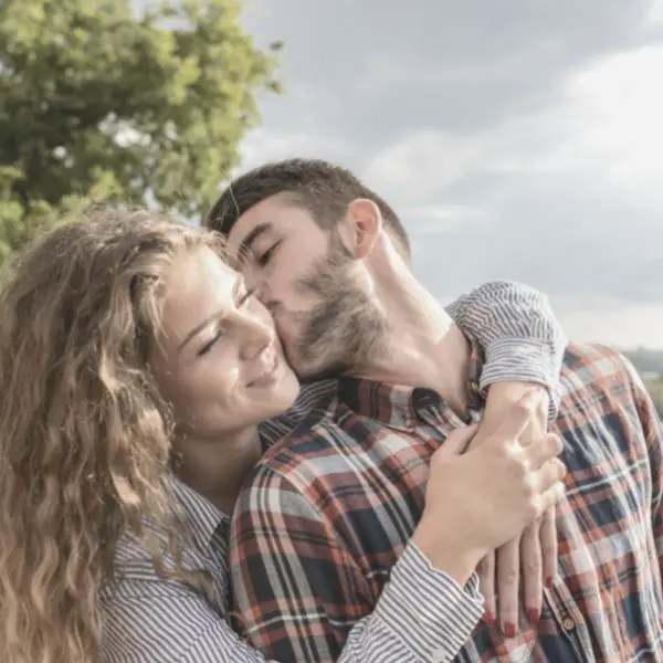 Woman hugging guy while he kisses her on cheek