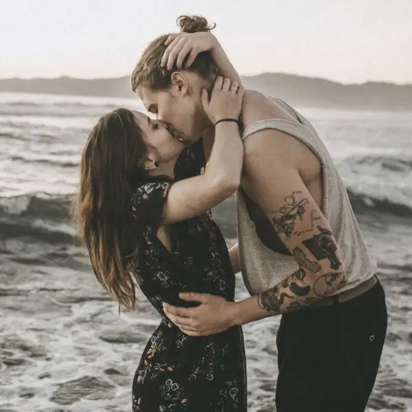 Woman kising a guy standing in the water at the beach