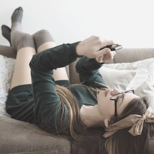 woman laying on sofa reading a text from a guy