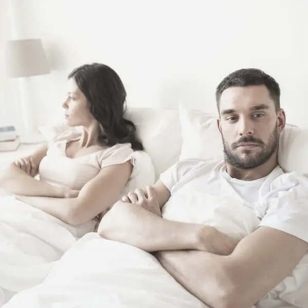 Couple in bed angry with arms folded