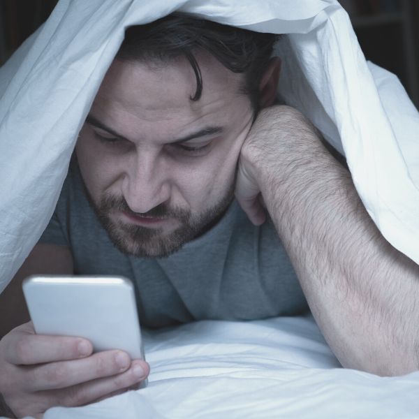 Guy depressed looking at social media in bed