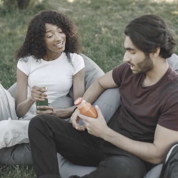 Guy and girl hanging out in the park talking drinking juices