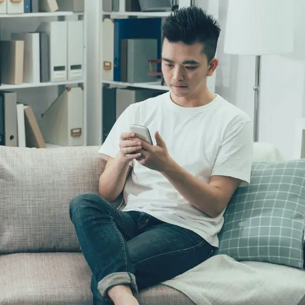 Guy sitting on couch texting a girl too much