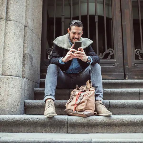 Guy sitting on steps smiling while texting a girl