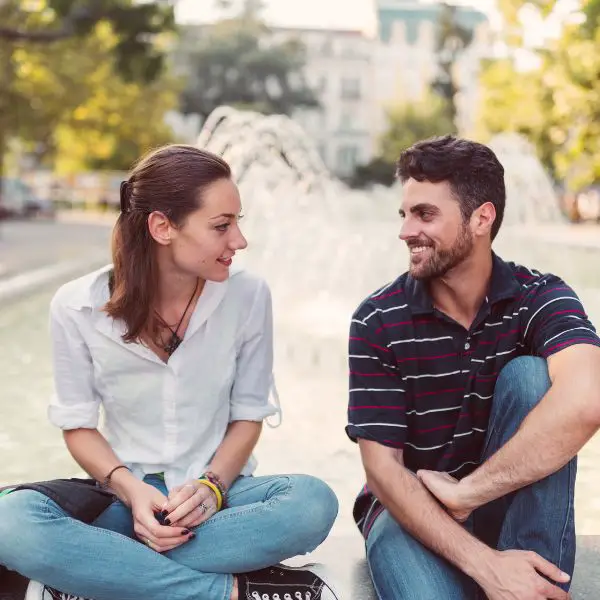 Man and woman siting in a park by the fountain talking