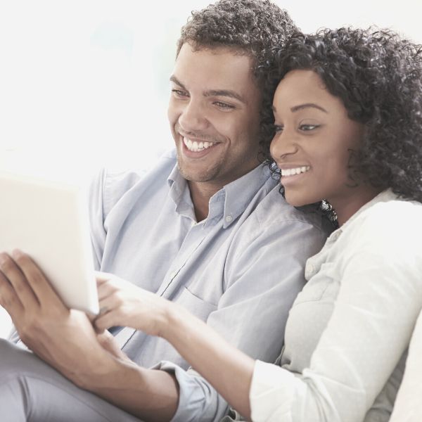 New couple hanging out on the couch looking at something on a tablet together