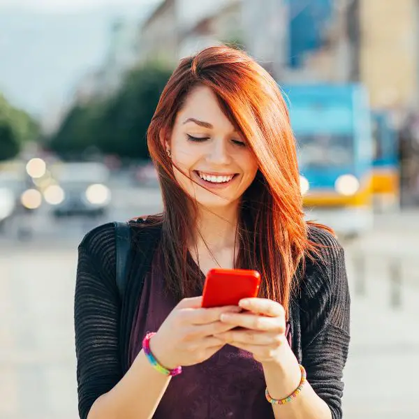 Woman with a big smile reading a text from a guy she just met