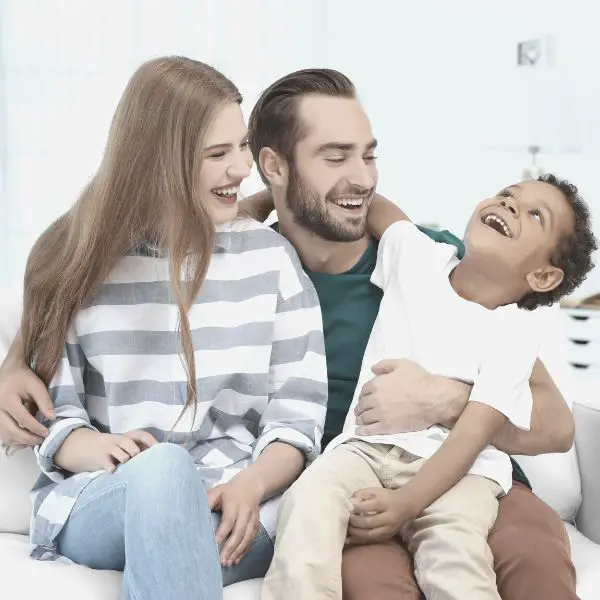 married couple sitting on couch with son laughing